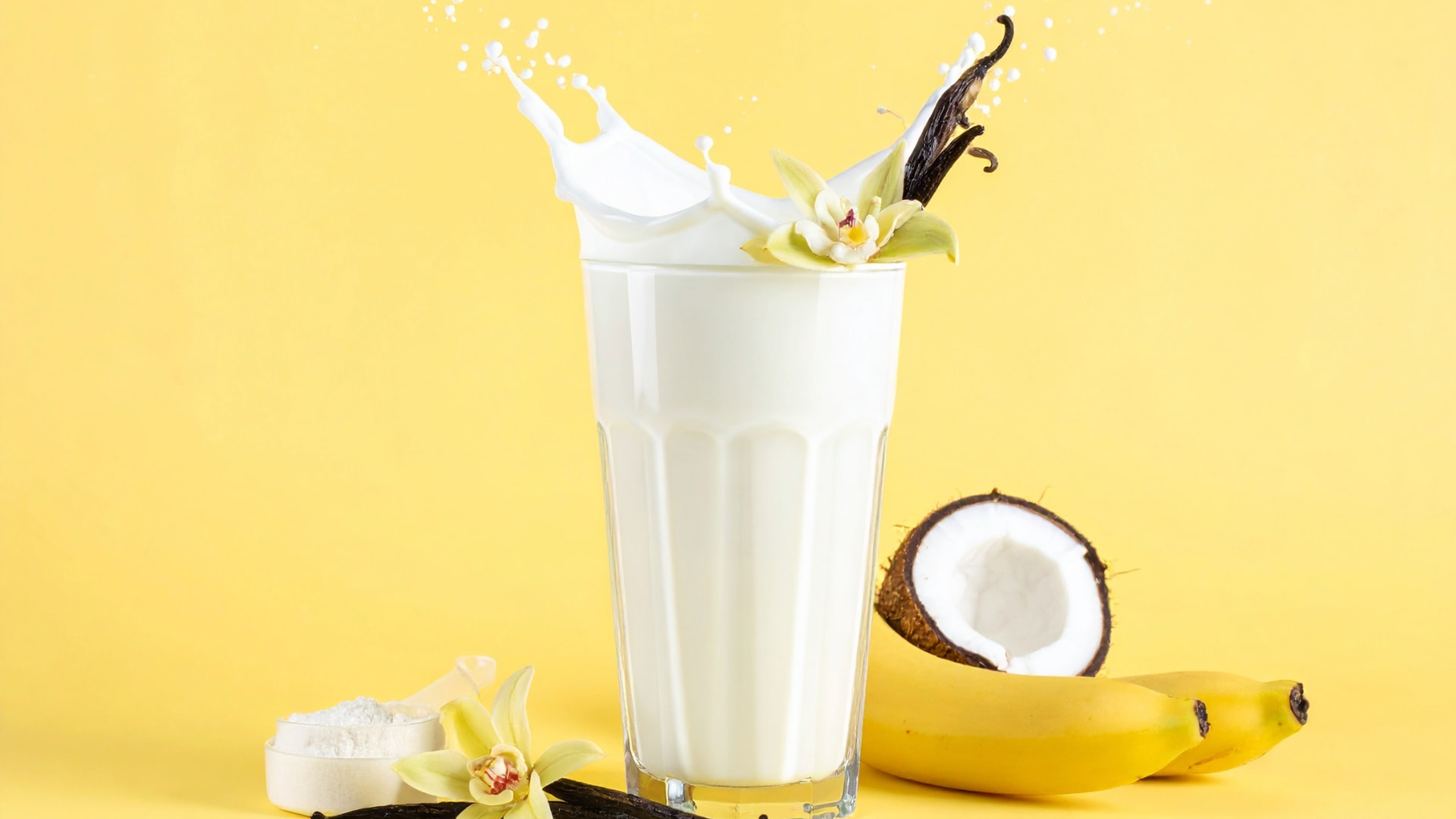 Glass with vanilla protein shake with bananas and coconout on the sides
