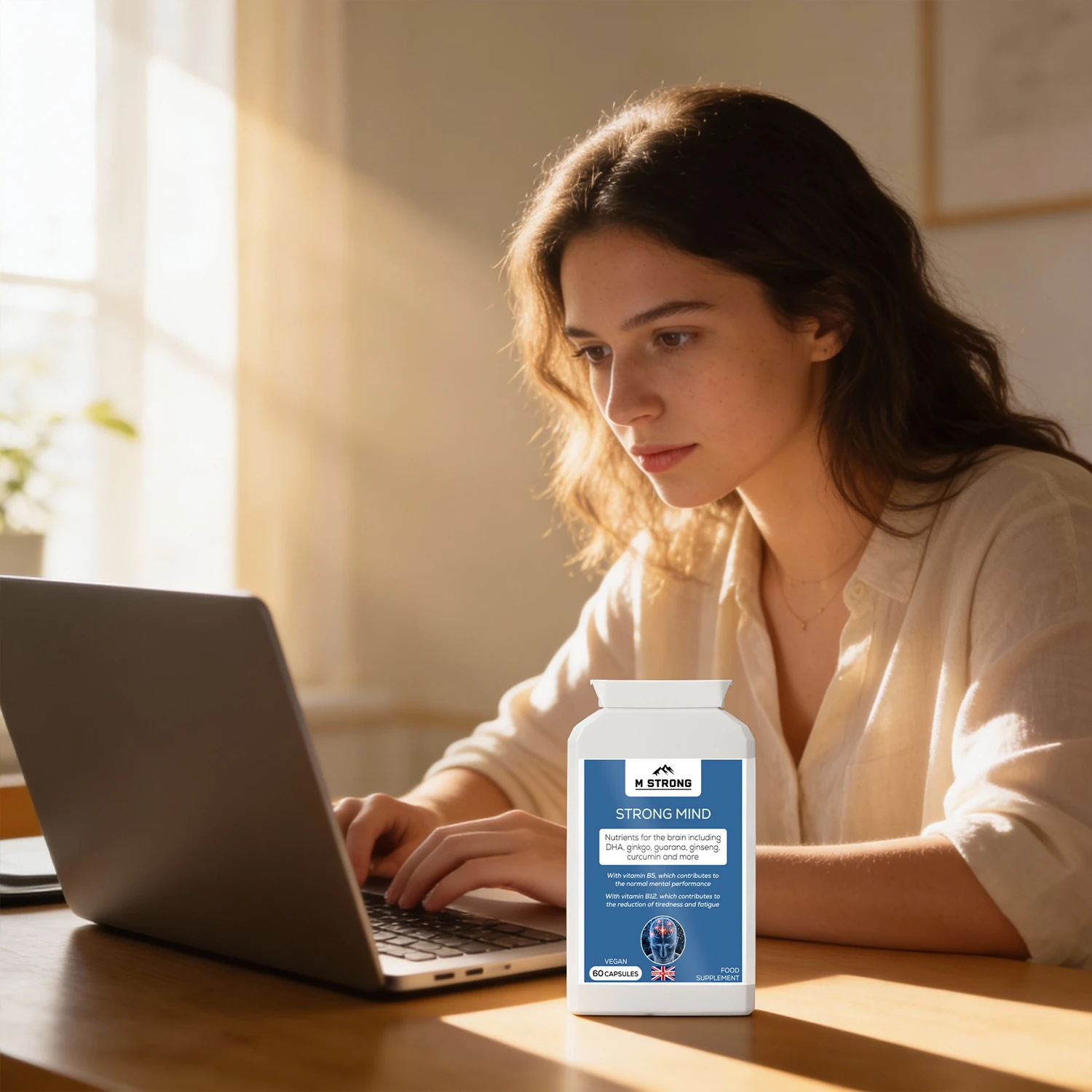 Woman working on a laptop with M STRONG Strong Mind supplement, supporting focus and mental performance during work